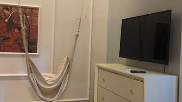 A modern room with a hanging hammock, a flat-screen TV, a minimalist dresser, and a checkered floor.