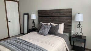 A bedroom with a bed, two bedside tables with lamps, a mirror, and a wooden headboard. - Perfect Retreat for Comfort and Convenience (Lincoln,)