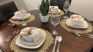 A dining table set with white plates, bowls, and silverware, surrounded by a brown tablecloth and a decorative doily. - Perfect Retreat for Comfort and Convenience (Lincoln,)