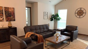 A modern living room with a leather sofa, two armchairs, a coffee table, and a large plant. - Perfect Retreat for Comfort and Convenience (Lincoln,)