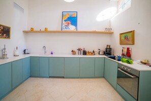 A kitchen with teal cabinets, a white countertop, and various kitchen appliances.