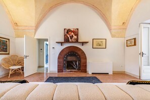 A room with a fireplace, a painting above it, and a door leading to another room.