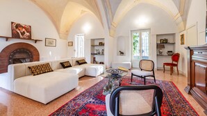 A spacious living room with a fireplace, a sofa set, a dining area, and a view through a window. - Vallone Apartment S, Galatina, Italy (Galatina)