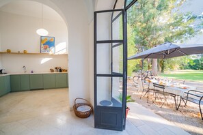 Een moderne keuken met groene kastjes, een hanglamp en een lijst met een foto aan de muur.