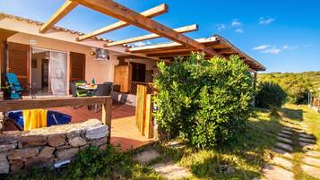 Un patio extérieur abrité, doté d’un mur en pierre, d’une pergola en bois et offrant une vue sur le paysage environnant.
