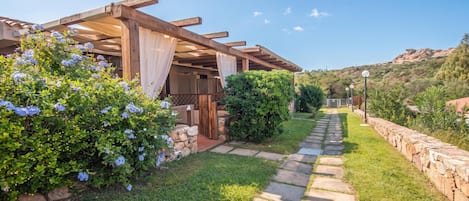 Un espace extérieur abrité, avec un chemin de pierre menant à un bâtiment.