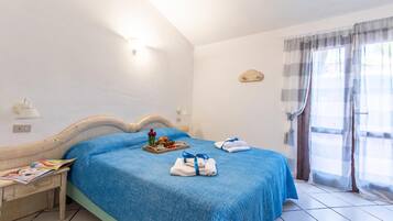 Une chambre d’hôtel avec un lit, une table de chevet, un plateau avec des articles pour le petit-déjeuner et une fenêtre avec des rideaux.