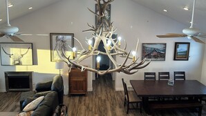 Amplia sala de estar con un gran candelabro, ventiladores de techo y un comedor con muebles de madera.