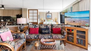 A living room with a sofa, coffee table, and a television displaying a beach scene.