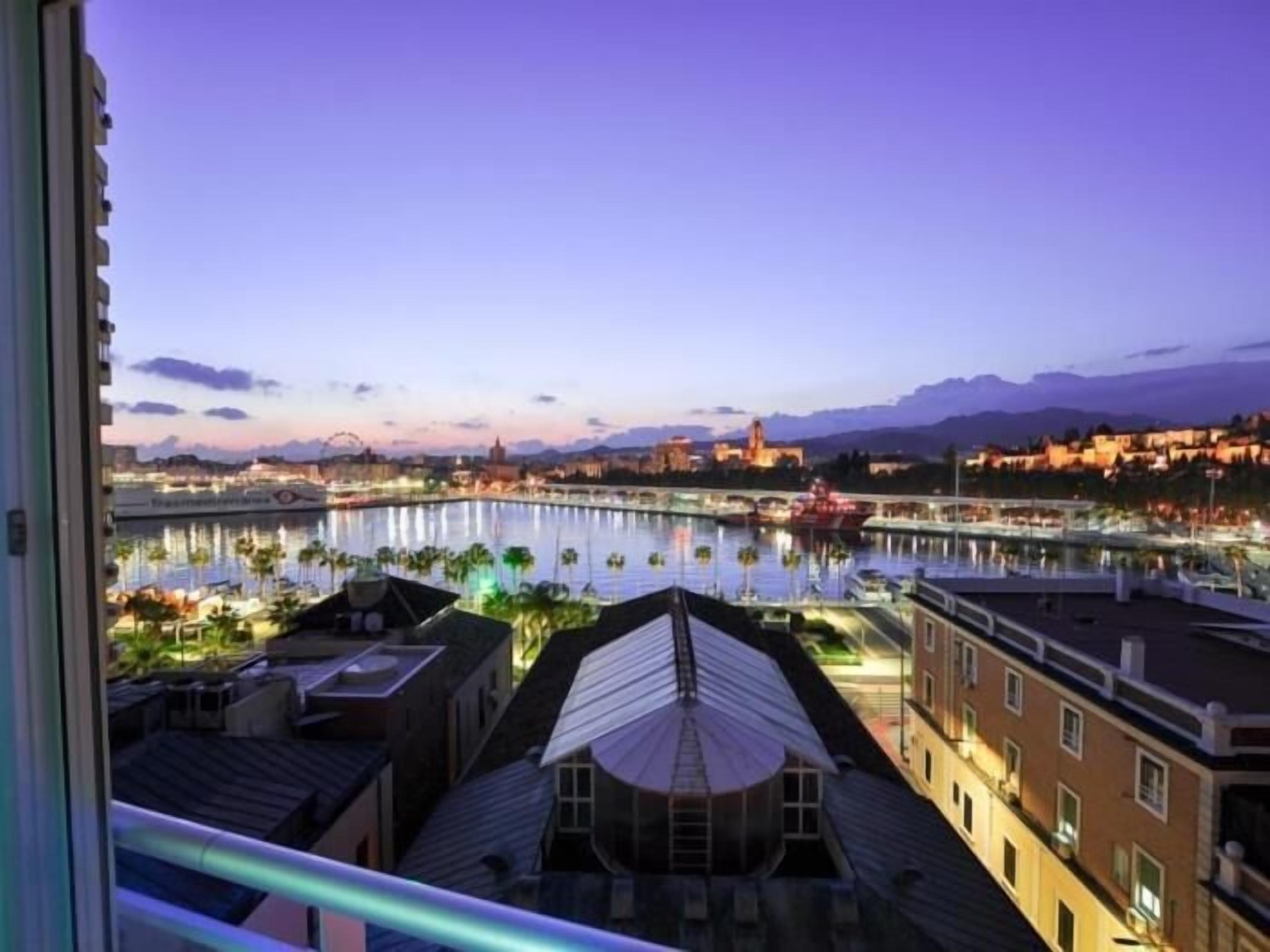 A view of a waterfront area with buildings, a river, and a distant mountain range.