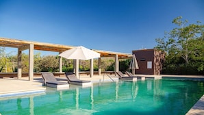 A swimming pool with lounge chairs and umbrellas, surrounded by a wooden pergola and a building. - Ocean/Mountain Views home in El Pescadero (El Pescadero)