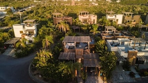 An aerial view of a residential area with multiple houses, surrounded by greenery and palm trees. - Ocean/Mountain Views home in El Pescadero (El Pescadero)