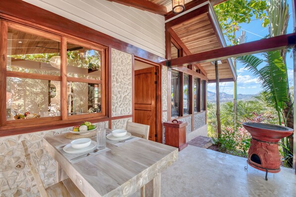 A dining area with a table set for two, a stone wall, and a view of the outdoors.