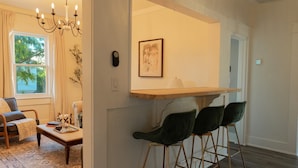 Un salon moderne avec un canapé, une table basse et un lustre. Il y a une fenêtre avec des rideaux et une vue sur les arbres.