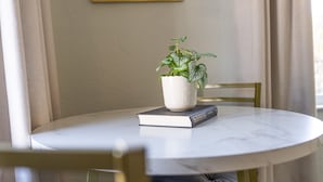 Une table ronde sur laquelle sont posés un pot de fleurs et un livre.