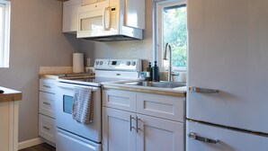 Une cuisine avec des meubles blancs, une cuisinière, un four à micro-ondes et un évier.