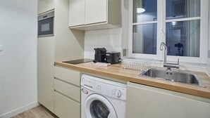 Une cuisine compacte équipée d’un lave-linge, d’une machine à café et d’un évier.