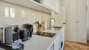 Et moderne køkken med indbygget espressomaskine, kaffemaskine og vask.