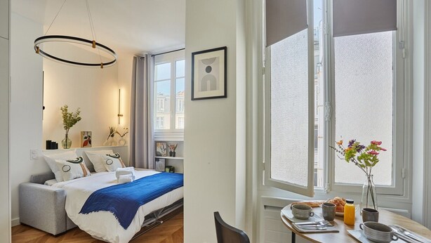 Et moderne hotelværelse med seng, sengebord og et spiseområde med bord og stole.