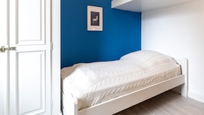 A bedroom with a single bed, a white wardrobe, and a blue accent wall. - Ferienwohnung in Vollerwiek Direkt am Nordseedeich (Vollerwiek)