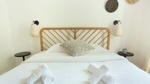 A neatly made bed with a wooden headboard, two bedside tables, and decorative wall hangings. - Lovely and new Apartment Center of Paris (Paris)