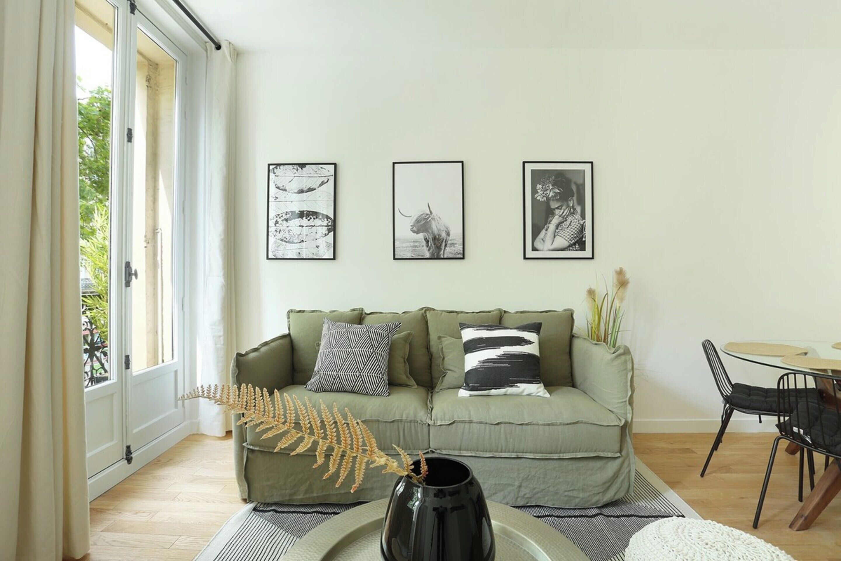 A living room with a sofa, a dining table, and framed pictures on the wall.