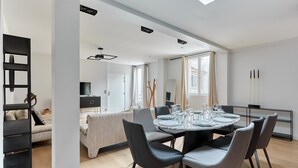 A modern dining area with a round table set for four, surrounded by grey upholstered chairs. - Superb Apartment Porte Maillot / Arc de Triomphe (Paris)