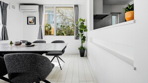 Une pièce moderne comprenant une table à manger, des chaises, une plante en pot et une fenêtre avec des rideaux.