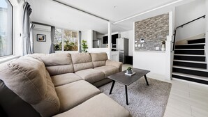 Un salon moderne avec un canapé d’angle, une table basse et un escalier menant à un niveau supérieur.