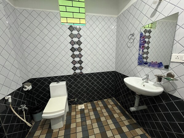 A bathroom with a toilet, sink, and shower area. - Hotel God's Gift (Morjim)