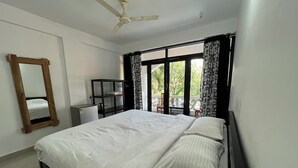 Una camera da letto con un letto, una ventola a soffitto, un armadio e una finestra con tende.