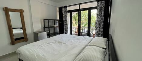 A bedroom with a bed, a ceiling fan, a wardrobe, and a window with curtains.