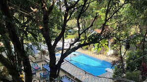 Un'area piscina con pavimento piastrellato, circondata da alberi e mobili da esterno.