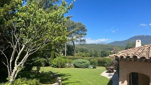 A well-maintained garden with a patio area, a stone pathway, and a view of a mountain range.
