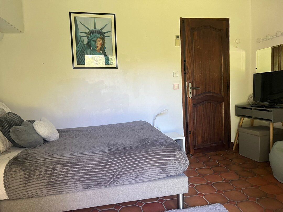 Une chambre à coucher avec un lit, une porte en bois, un téléviseur et un tableau encadré au mur.