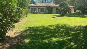 A house with a tiled roof, a covered porch, and a well-maintained lawn.
