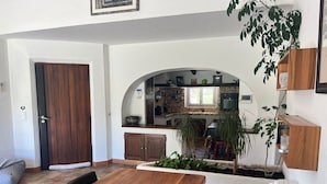 A modern kitchen with a central island, a dining area with a wooden table and chairs, and a small indoor garden.
