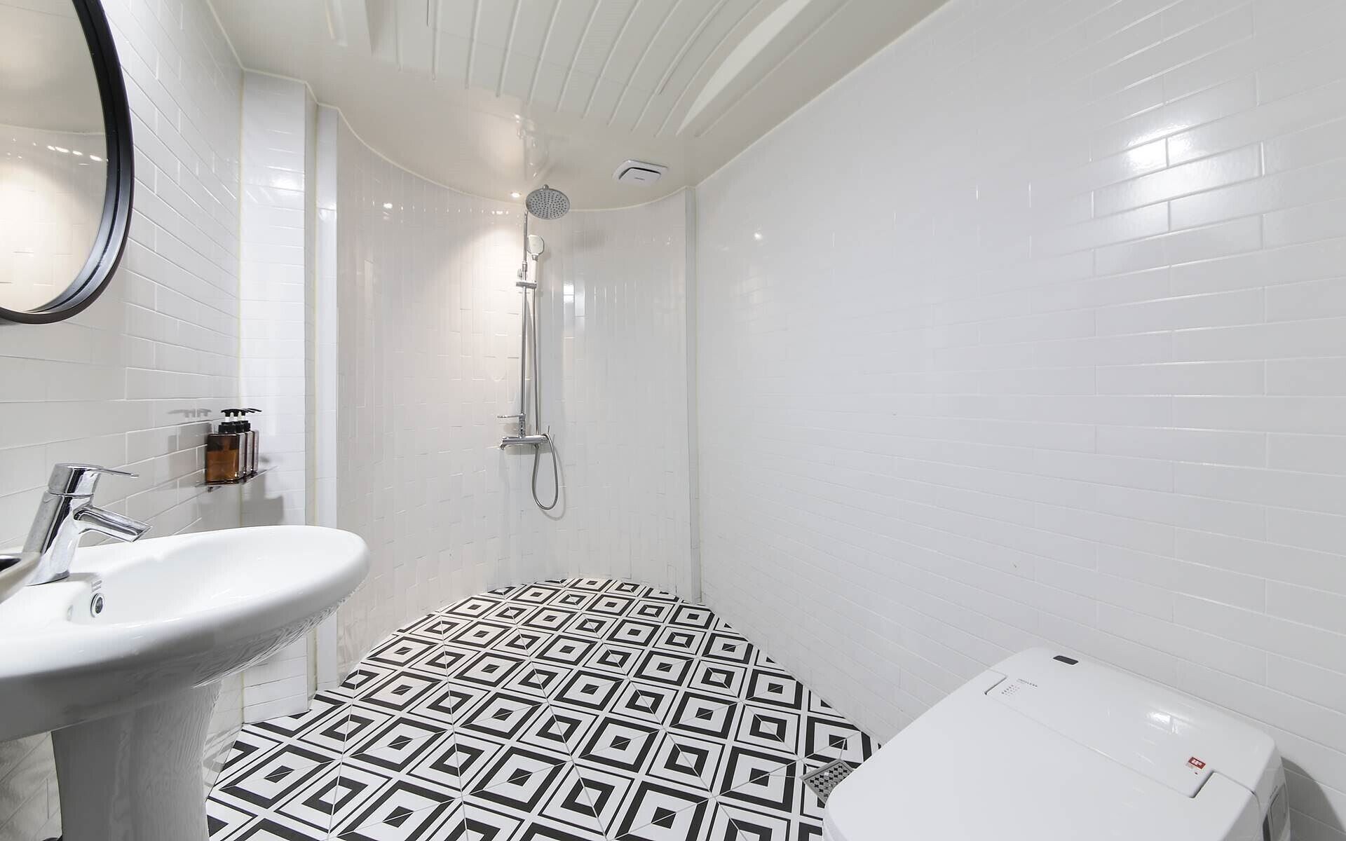 A bathroom with a white sink, a shower with a handheld showerhead, and a toilet.