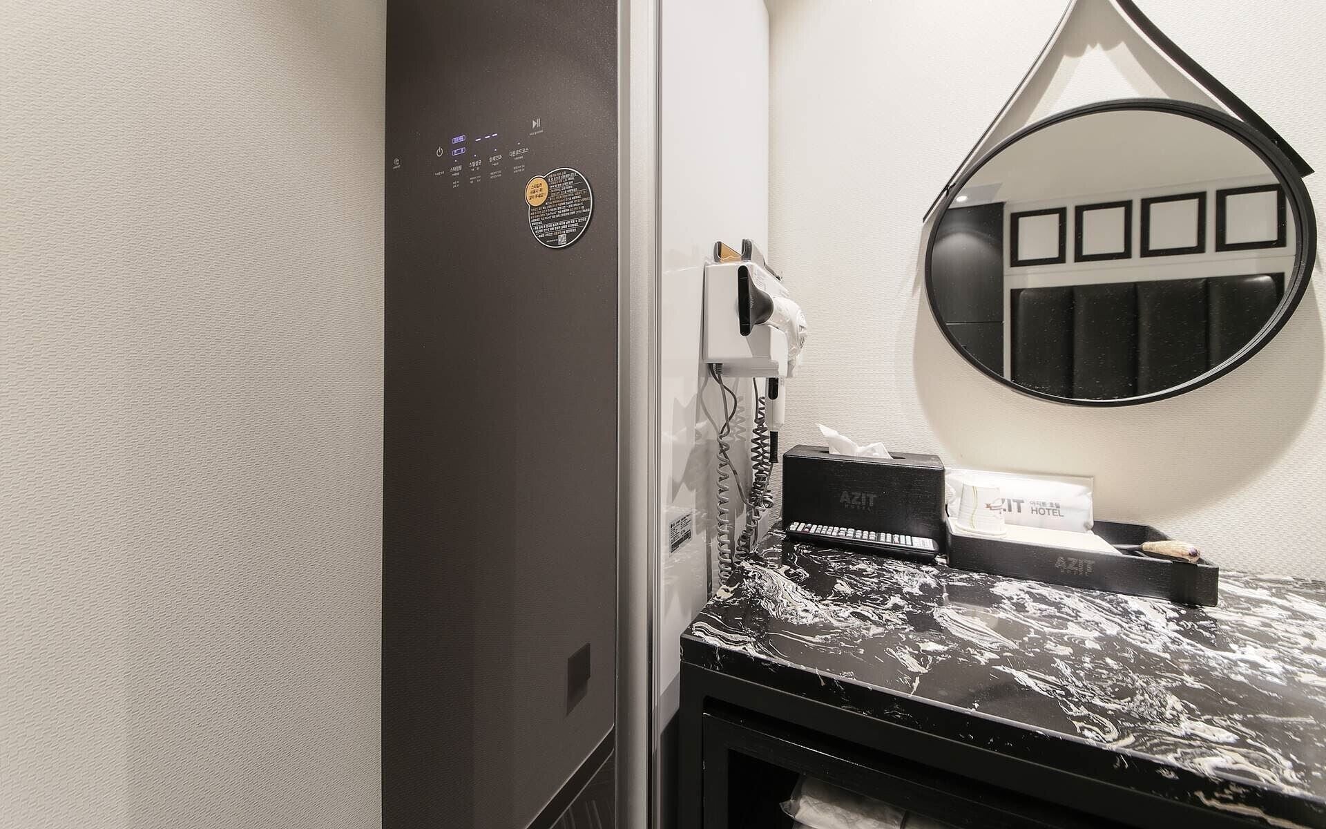 A hotel room with a black marble countertop, a mirror with a black frame, and a sign that reads "HOTEL".