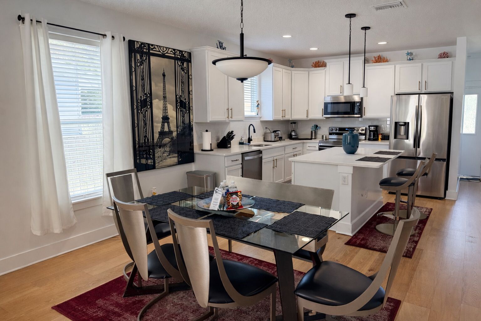 A modern kitchen with white cabinets, stainless steel appliances, and a dining area with a glass table and chairs.