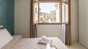A hotel room with a bed, a window with curtains, and a view of a cityscape. - Nice apartment for 4 guests with A/C, WIFI, TV and terrace (Balestrate-foce)