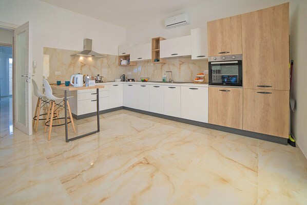 A modern kitchen with white cabinets, a wooden cabinet, a built-in oven, and a marble floor. - Villa Na' Lu' 1 With Sea View (Lecce)