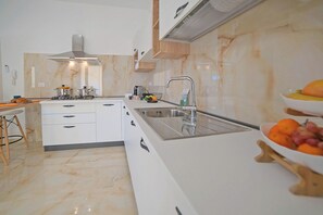 A modern kitchen with white cabinets, a stainless steel sink, and a marble backsplash. - Villa Na' Lu' 1 With Sea View (Lecce)