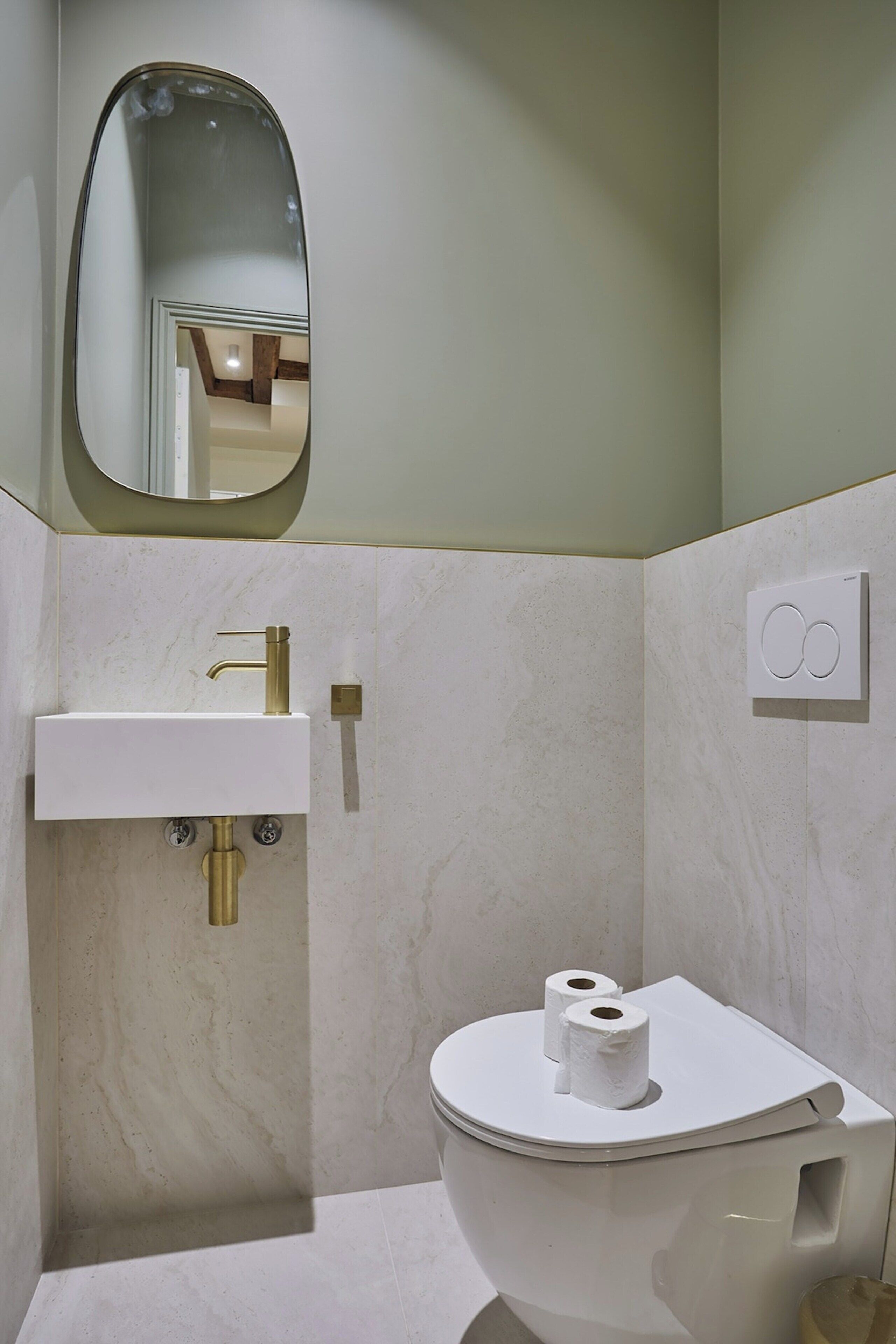Ein Badezimmer mit einem weißen Waschbecken, einer Toilette und einem Spiegel.