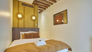 Ein Schlafzimmer mit einem hölzernen Kopfende, einem Bett mit brauner Bettwäsche und zwei Wandleuchten.