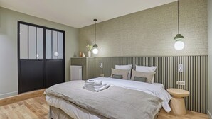 Ein modernes Schlafzimmer mit einem großen Bett, Nachttischen, Holzboden und einer Wand mit Grüner Struktur.