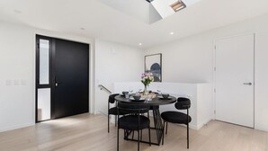 A modern dining area with a round table, black chairs, and a vase of flowers.