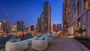 Eine Dachterrasse mit Sitzgelegenheiten im Freien und Blick auf eine städtische Skyline im Abendrot.