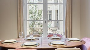 A dining table set for four with a view of a balcony and buildings. - Sublim Apartment Arc de Triomphe/ Trocadero (Paris)