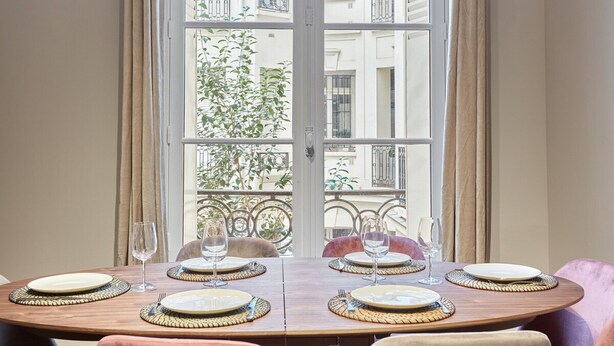 A dining table set for four with a view of a balcony and buildings.